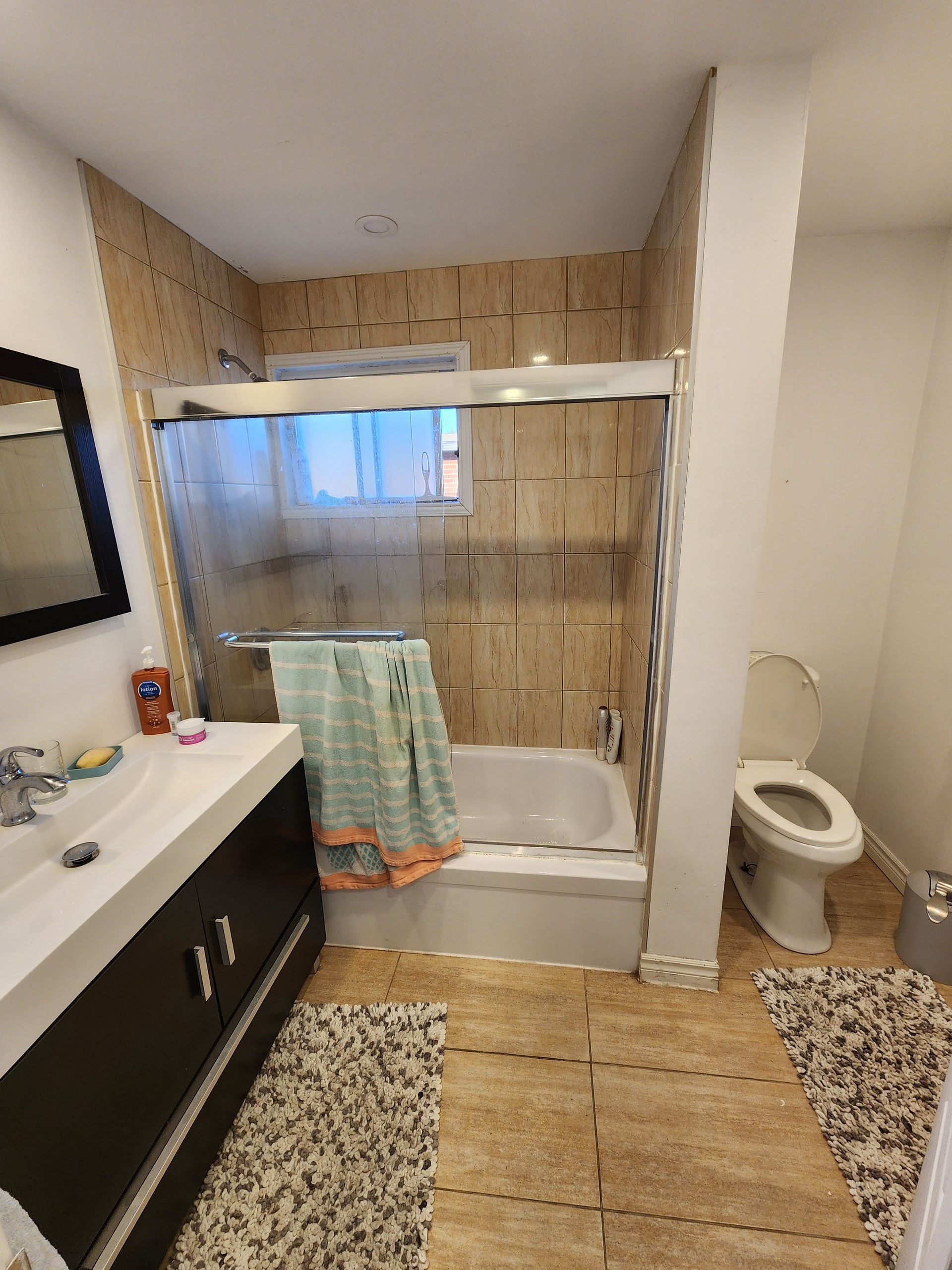 Une salle de bain avec baignoire , WC , lavabo et miroir.