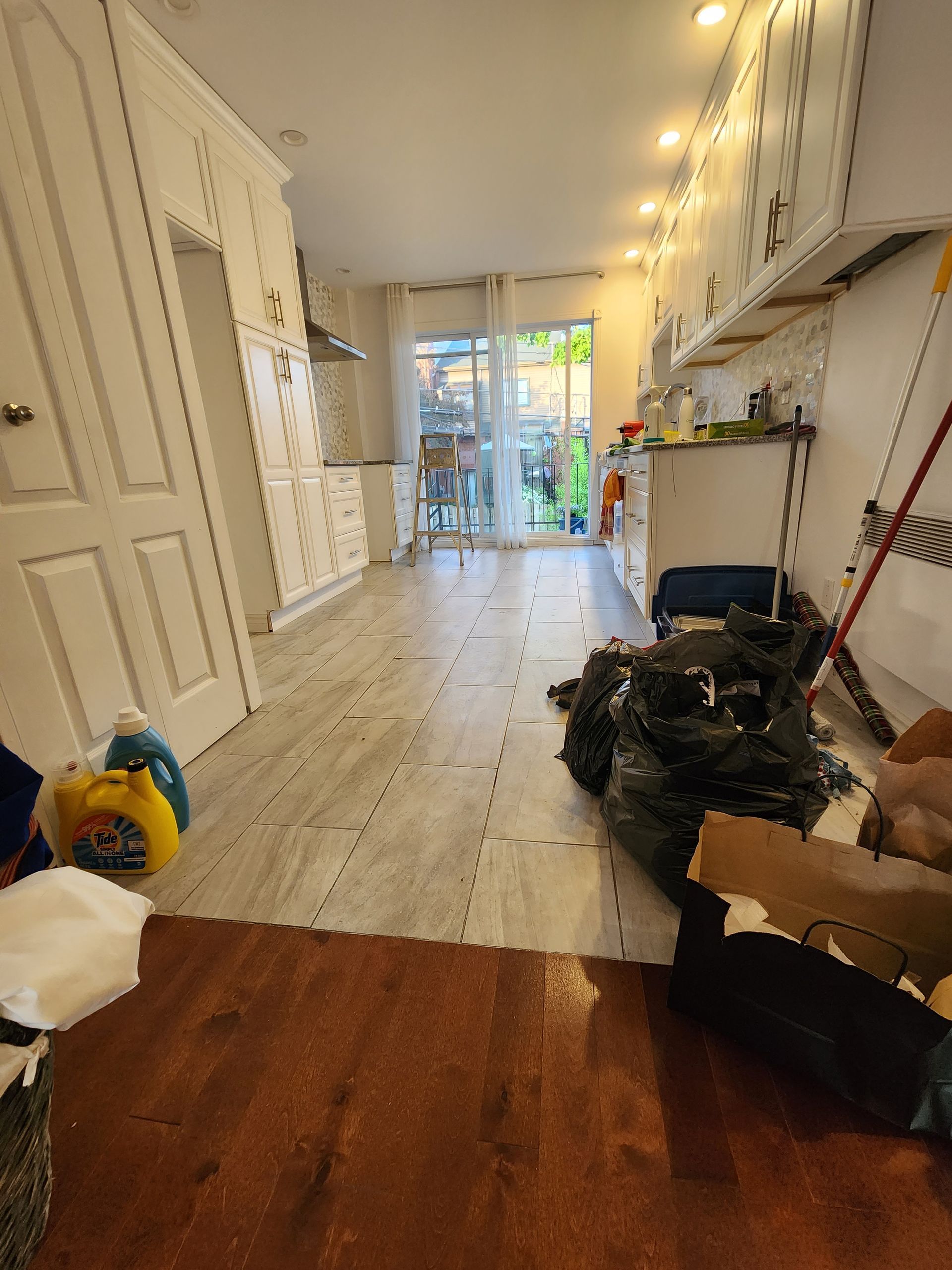 Une cuisine avec parquet et armoires blanches est en cours de rénovation.