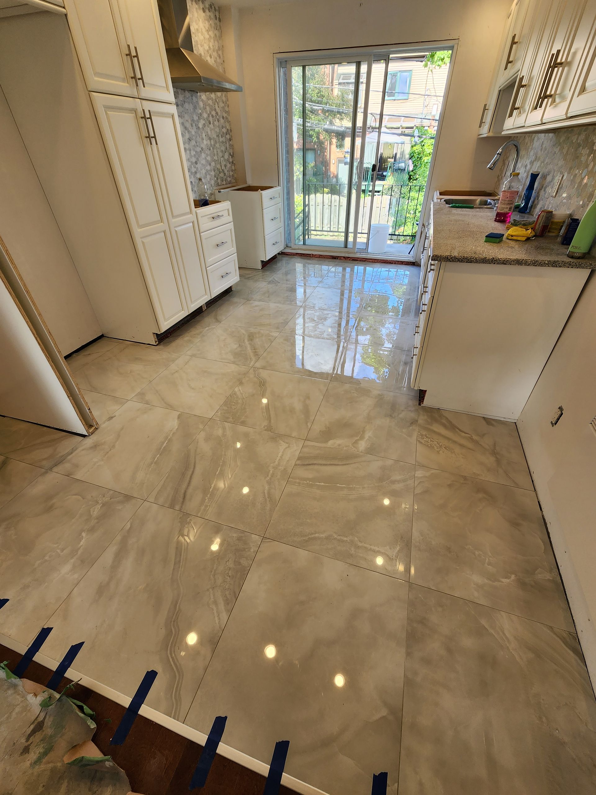 Une cuisine avec un sol en marbre et des portes coulissantes en verre.