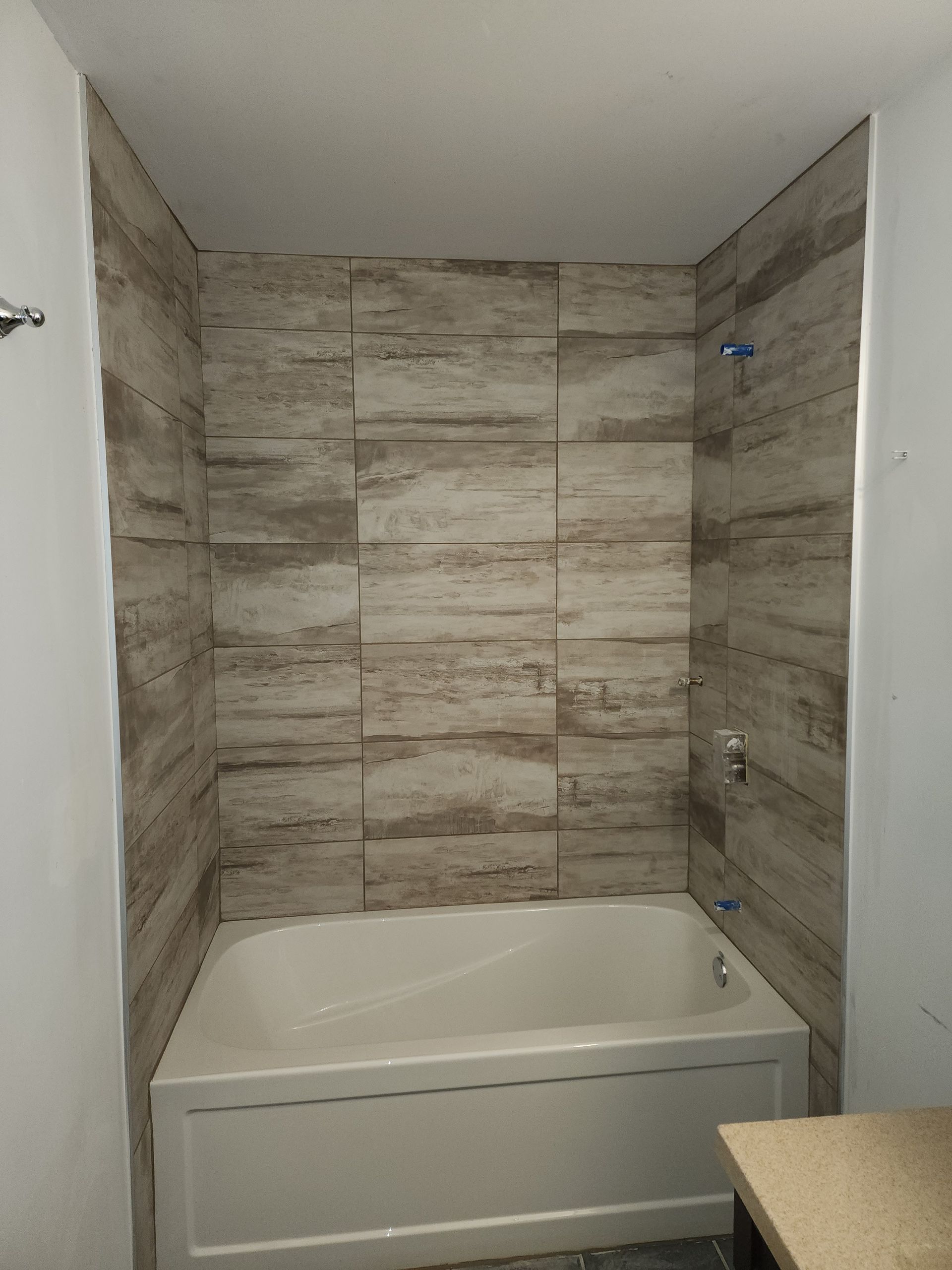 Une salle de bain avec baignoire et murs carrelés.