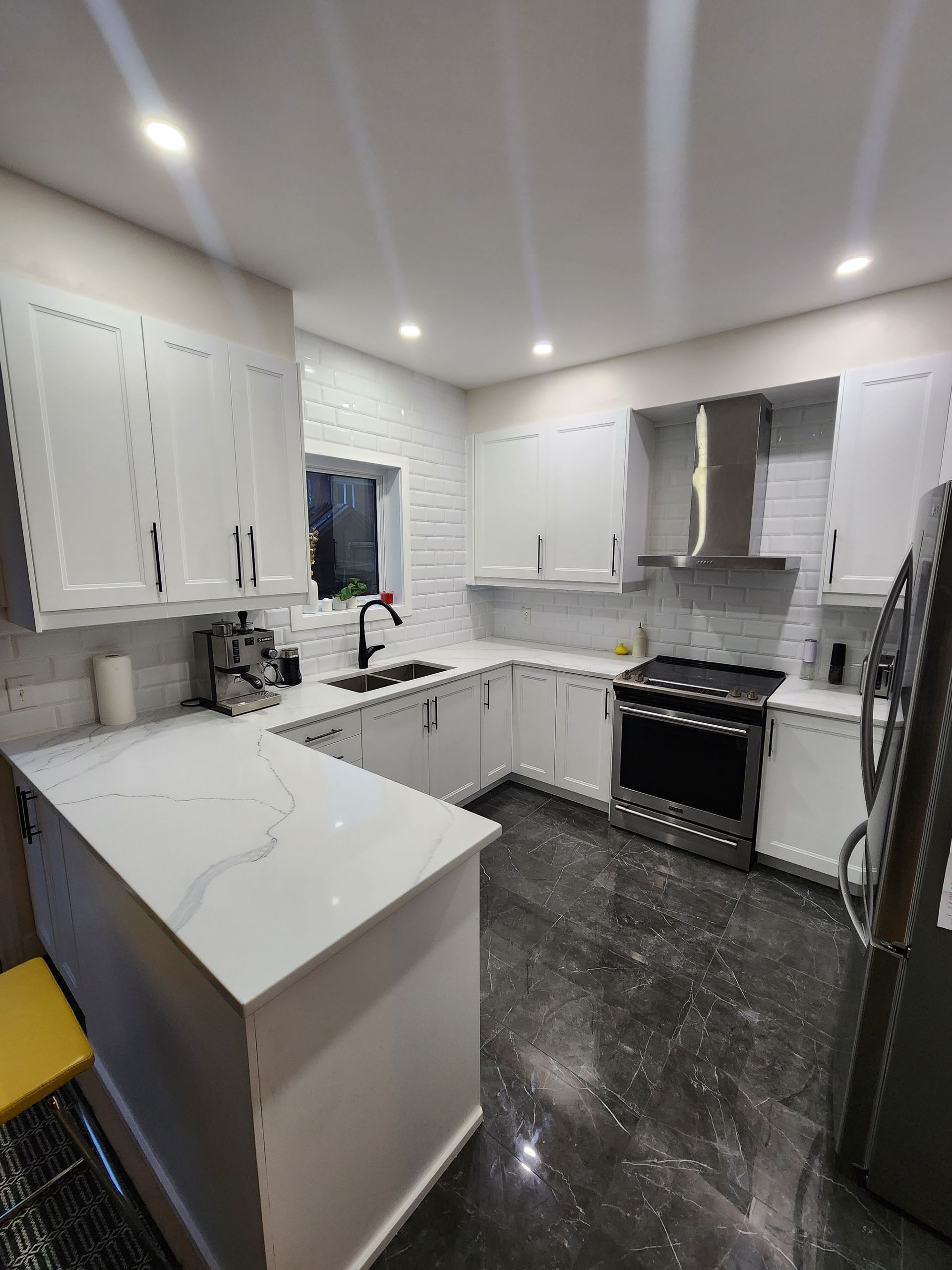 Une cuisine avec des armoires blanches, une cuisinière, un réfrigérateur et un évier.