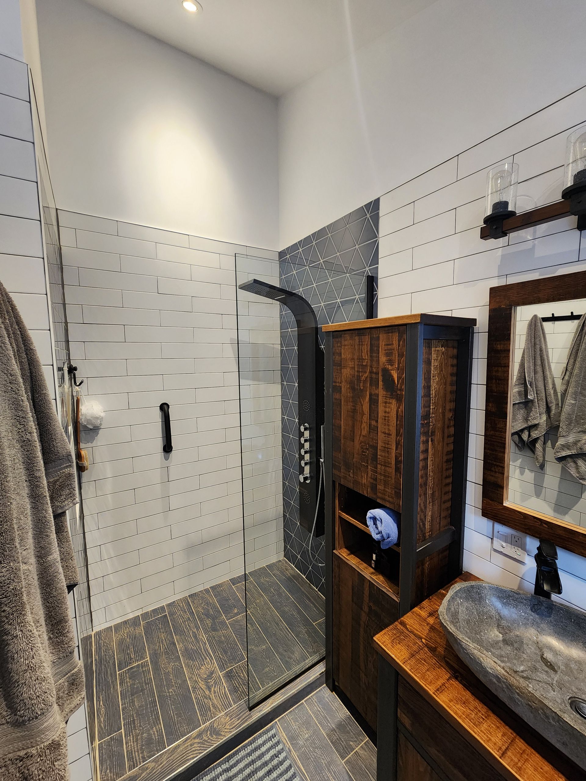 Une salle d'eau avec douche à l'italienne, lavabo et miroir.