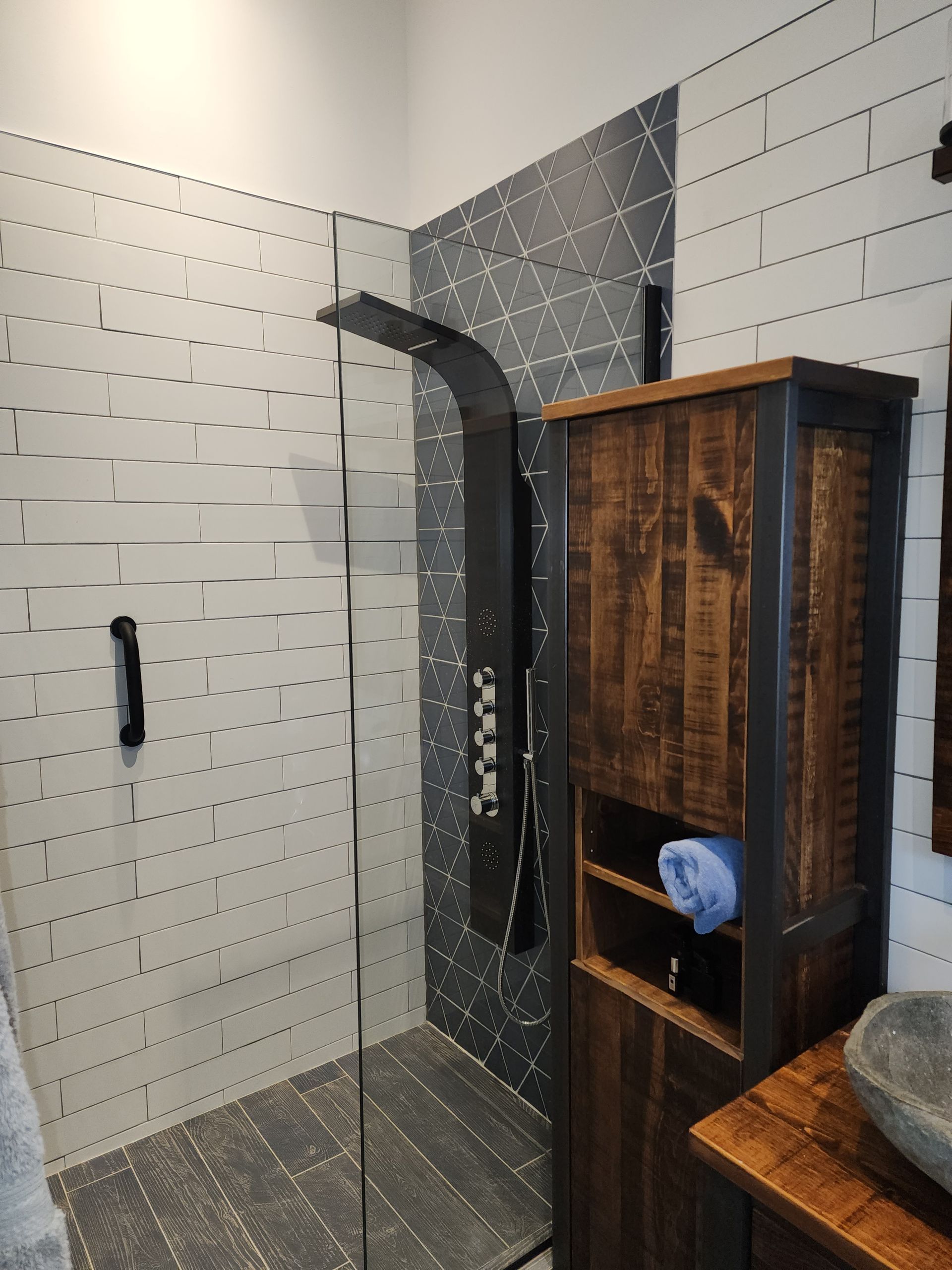 Une salle d'eau avec douche à l'italienne et meuble en bois.