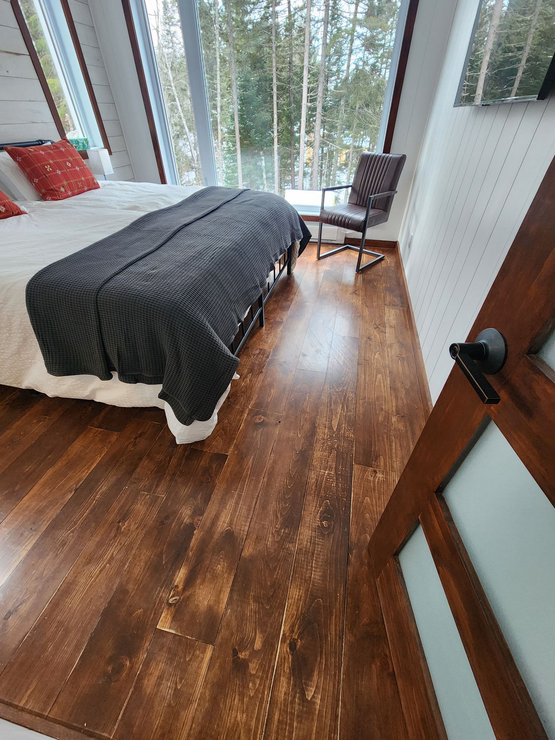 Une chambre avec un lit , une chaise et de grandes fenêtres.