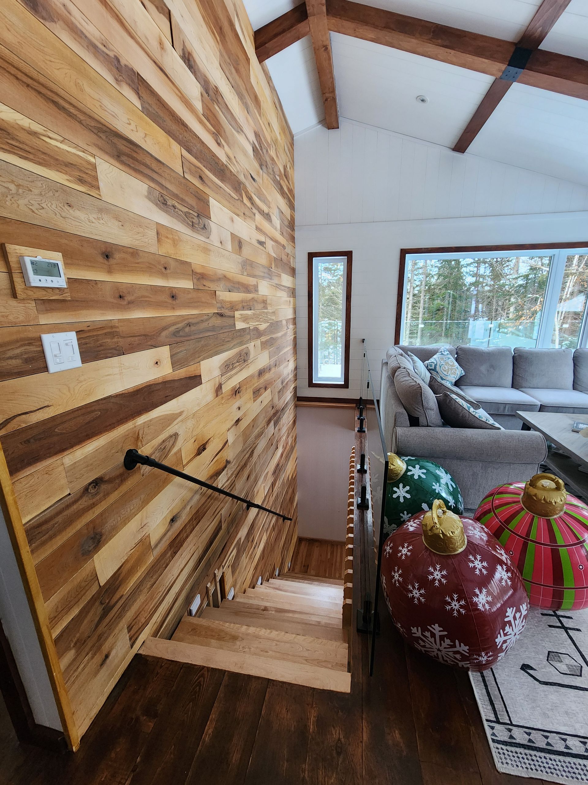 Un salon avec un mur en bois et des escaliers menant au deuxième étage.