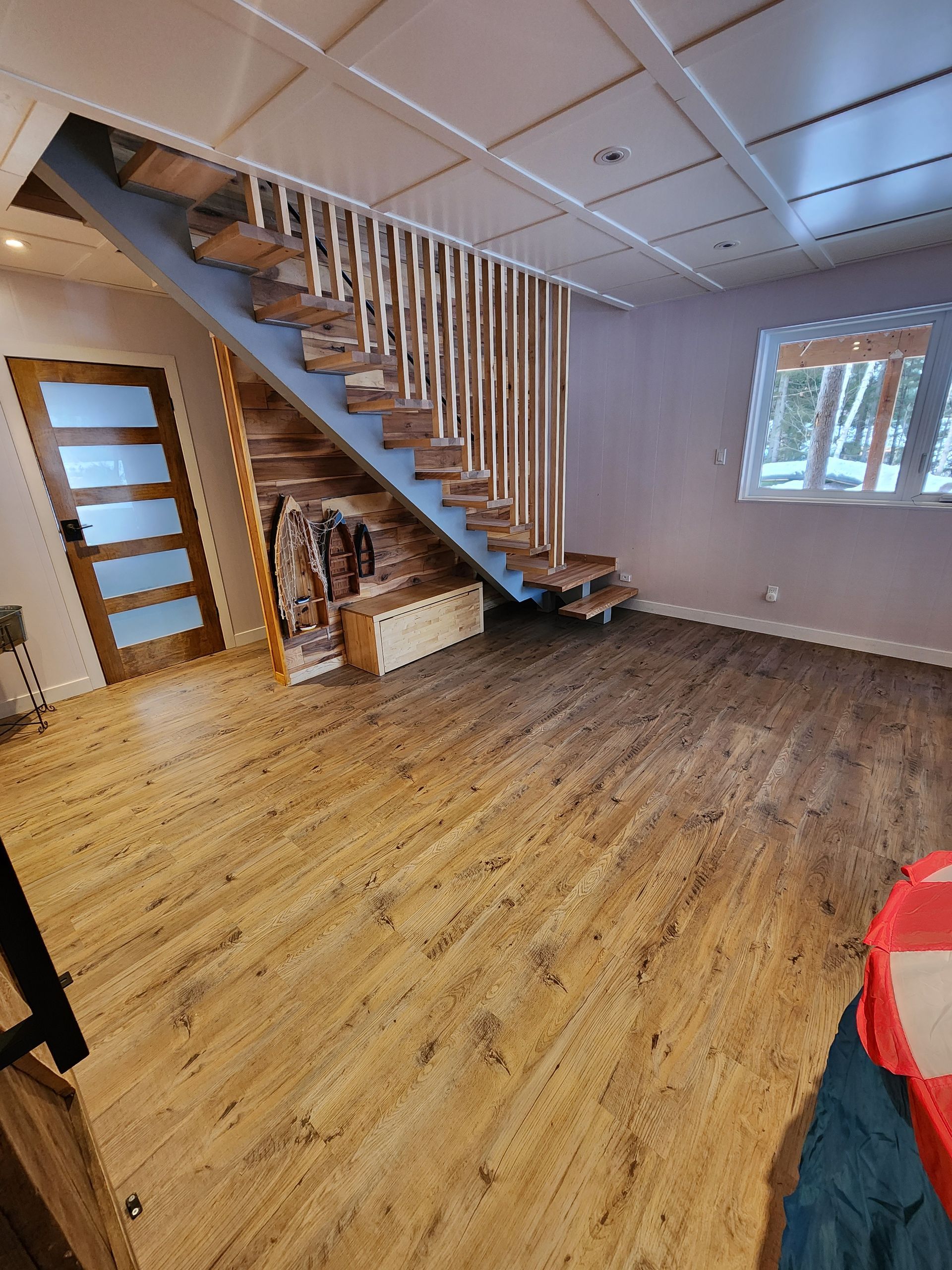 Un salon avec un escalier en bois et du parquet.