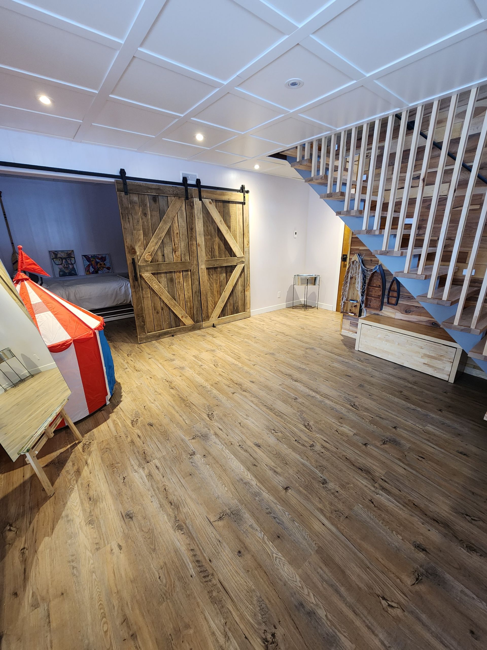 Une pièce avec un escalier et une porte de grange coulissante.