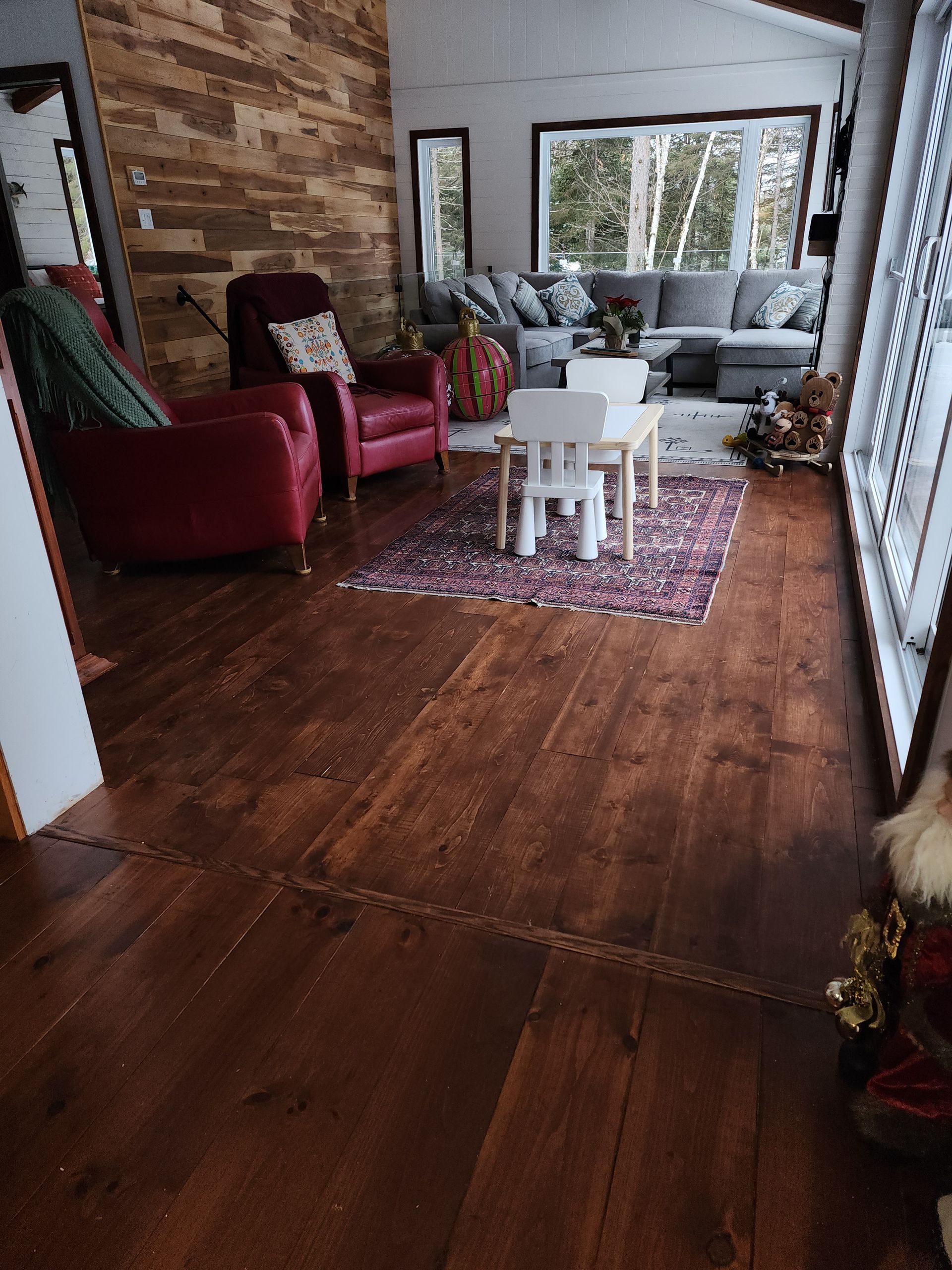Un salon avec parquet, un canapé, des chaises et une table.