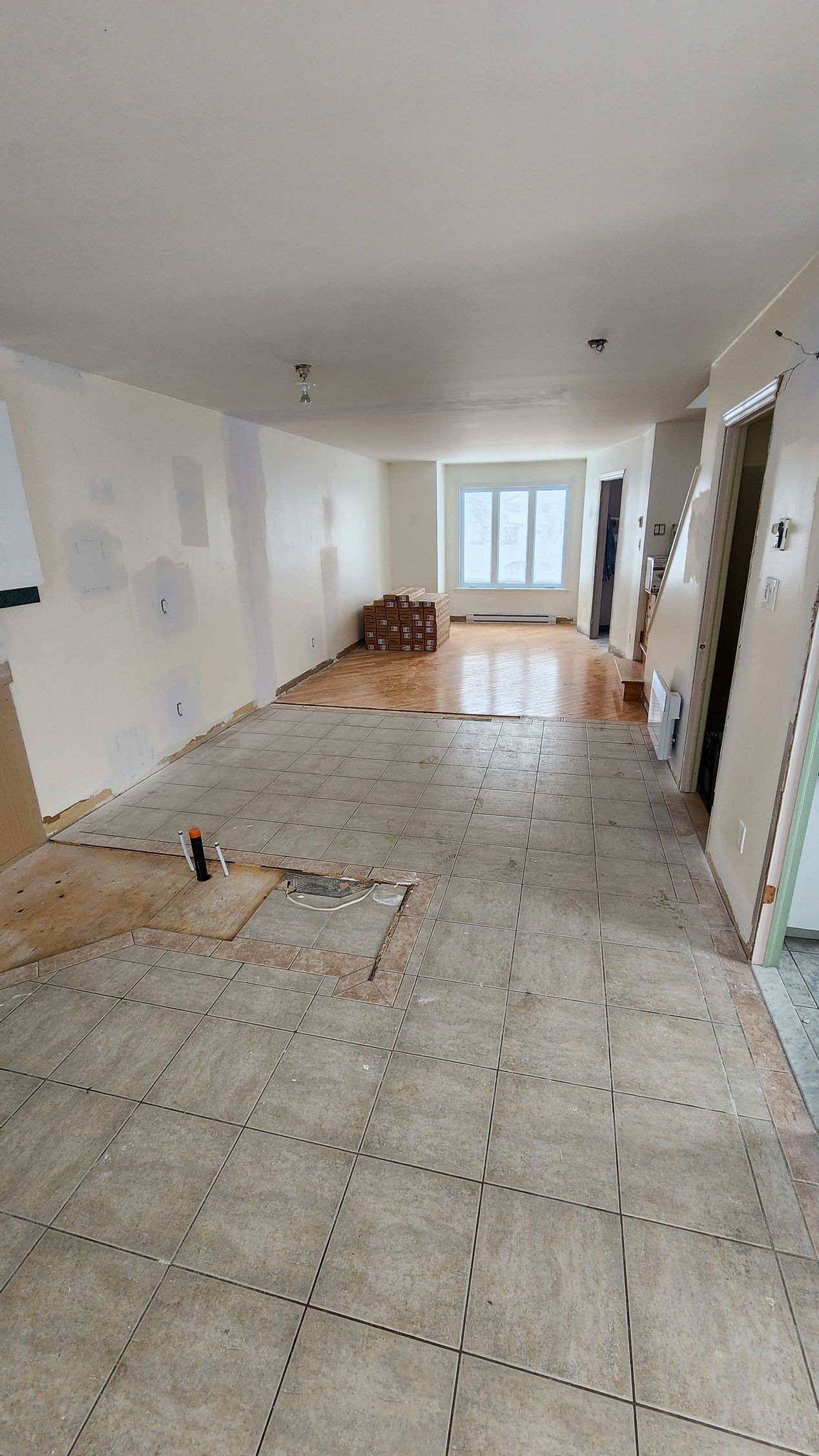 Une grande pièce vide avec un sol carrelé et des murs blancs.