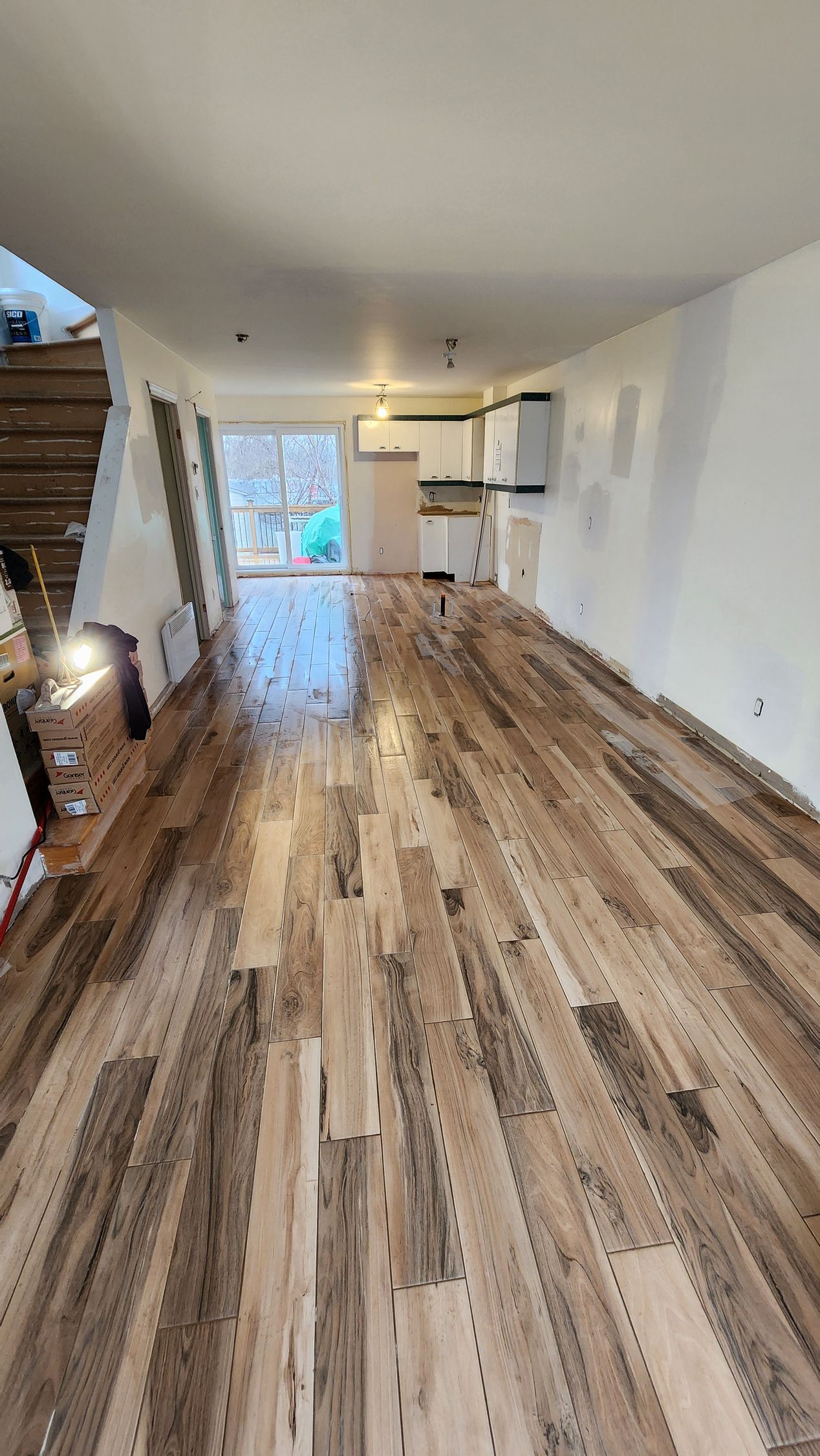 Une grande pièce vide avec un parquet et des escaliers en bois.