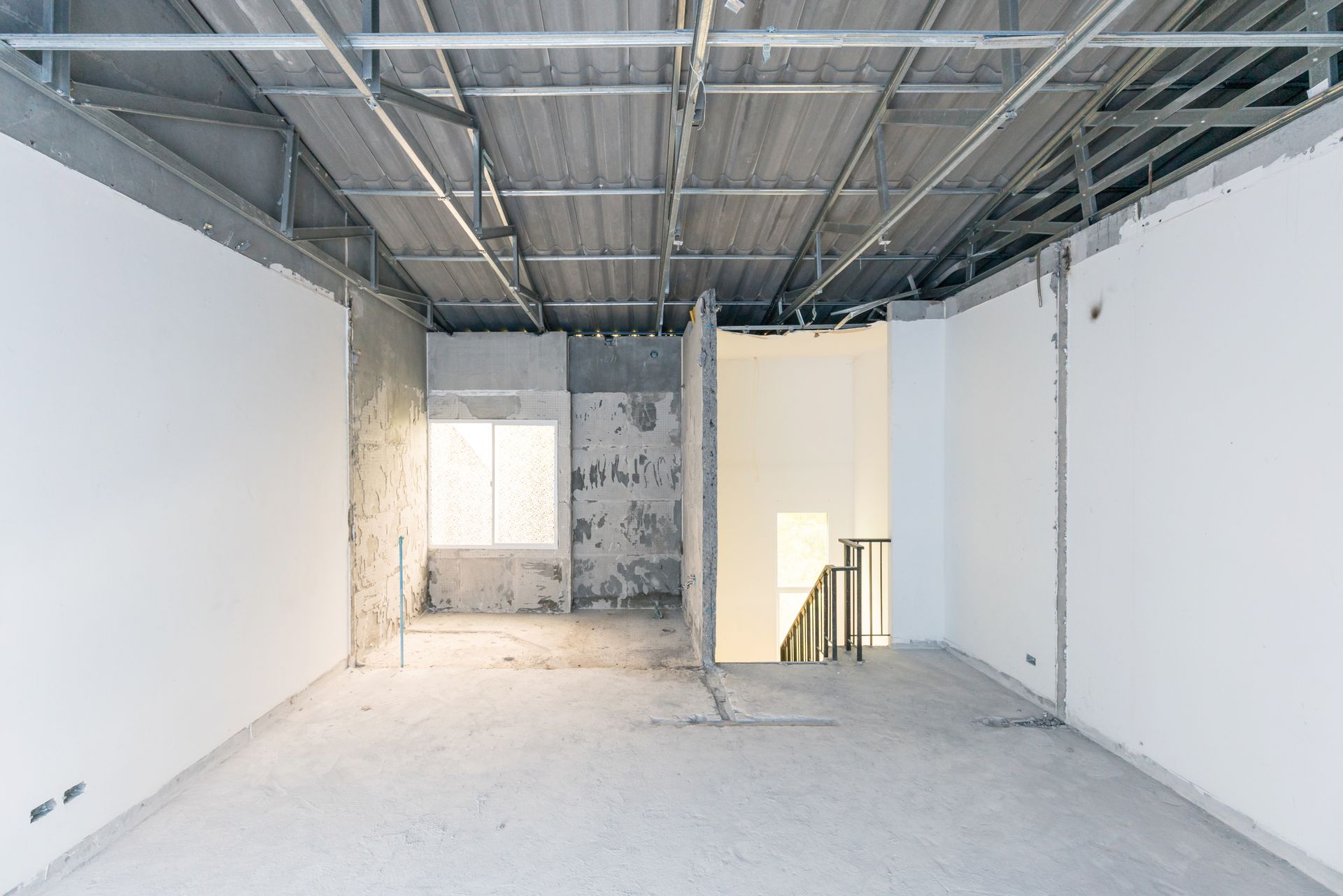 Une grande pièce vide avec des murs blancs et un plafond en métal.