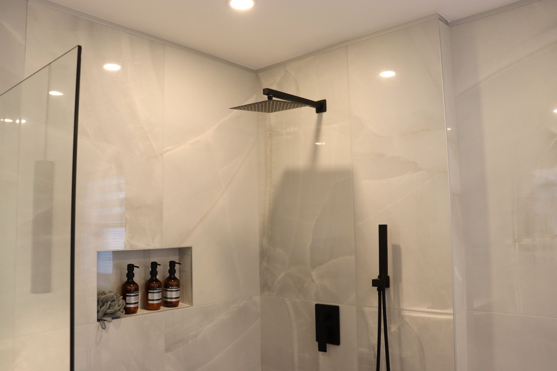 Une salle de bain avec douche à l'italienne et pomme de douche.