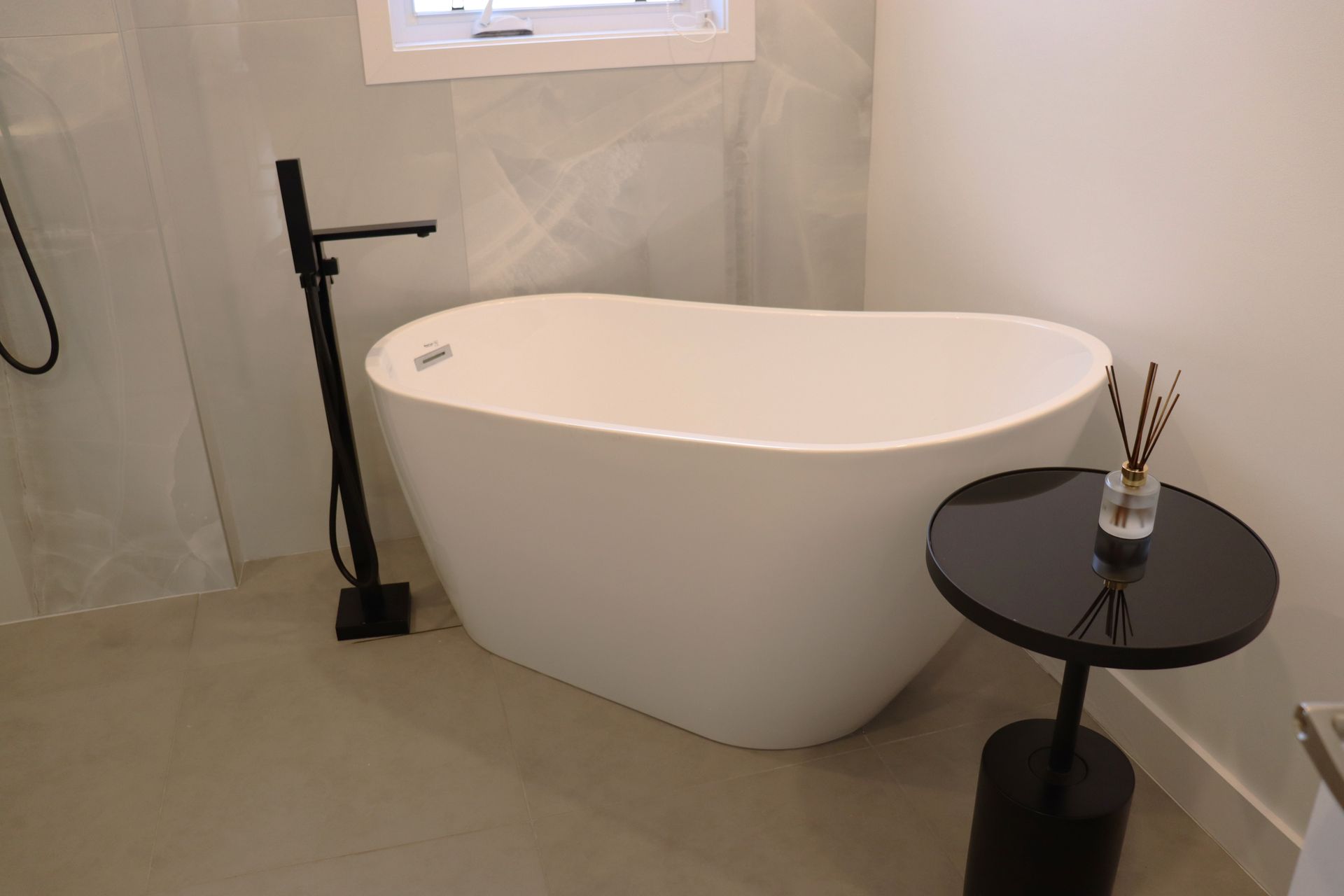 Une baignoire blanche se trouve à côté d'une table noire dans une salle de bain.