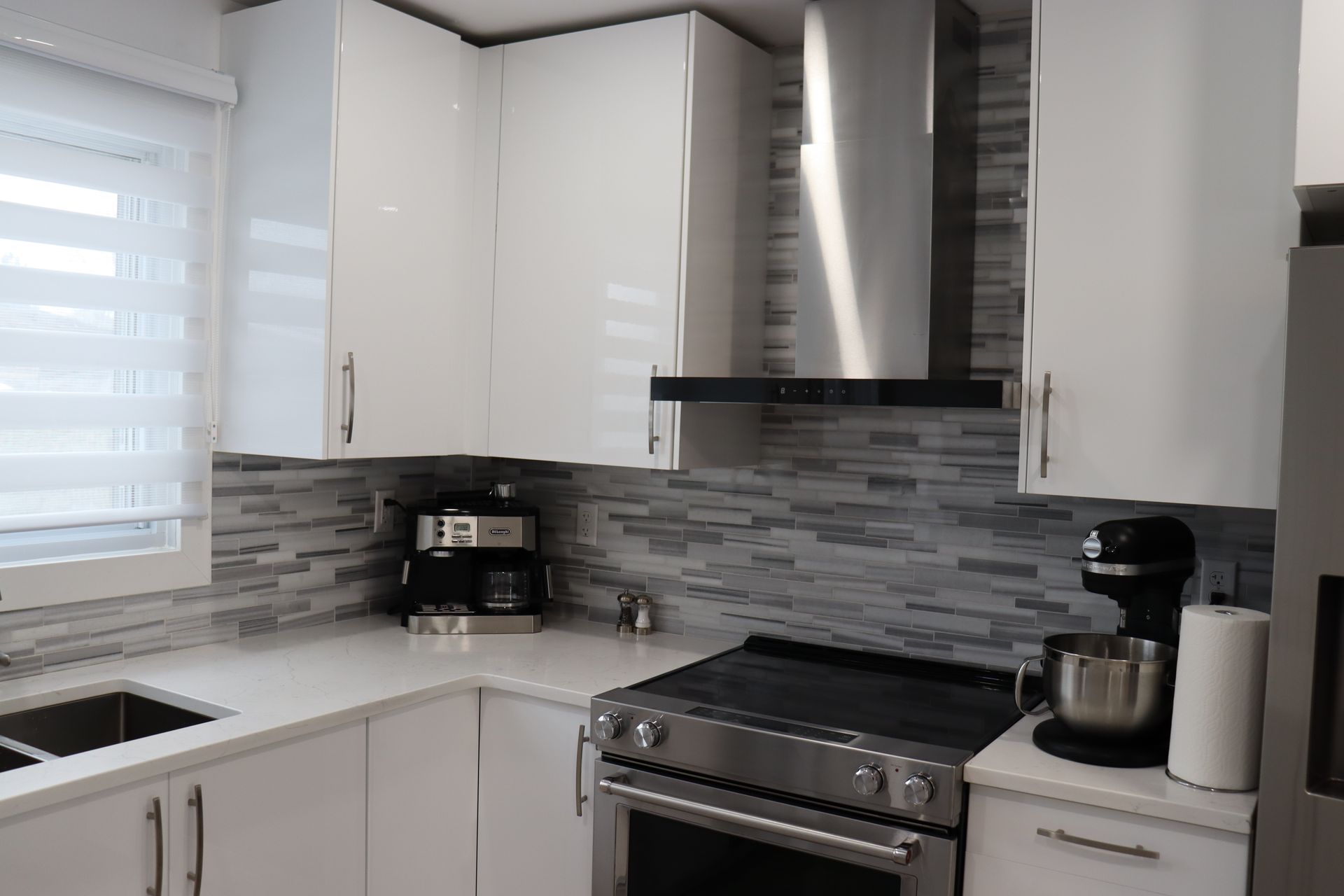 Une cuisine avec armoires blanches et appareils électroménagers en acier inoxydable.