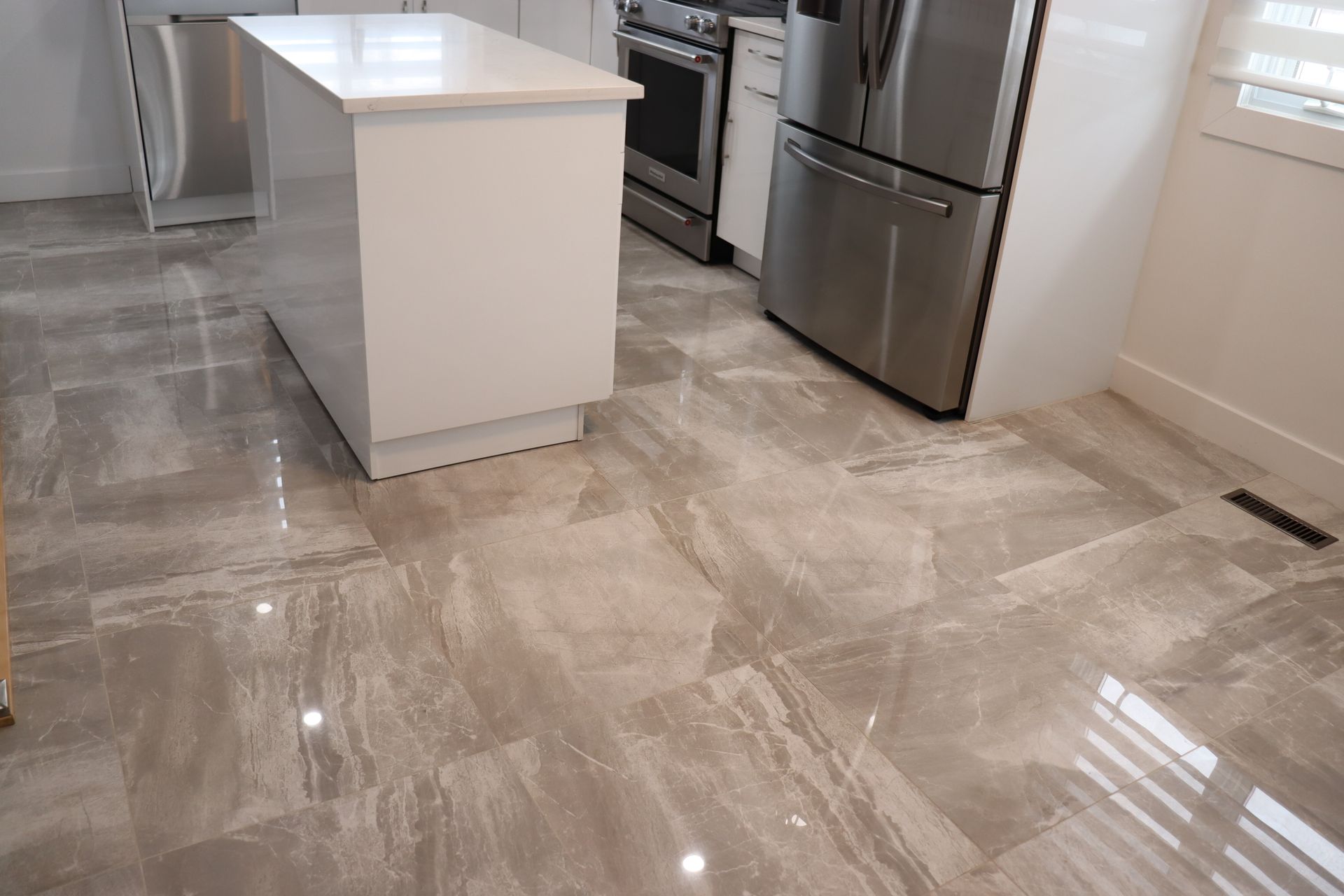 Une cuisine avec appareils électroménagers en acier inoxydable et carrelage au sol.