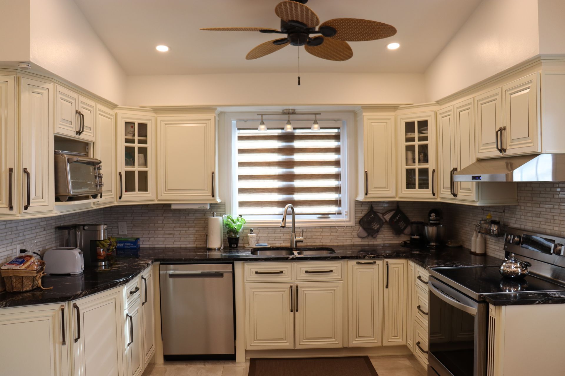 Une cuisine avec des armoires blanches et un ventilateur de plafond