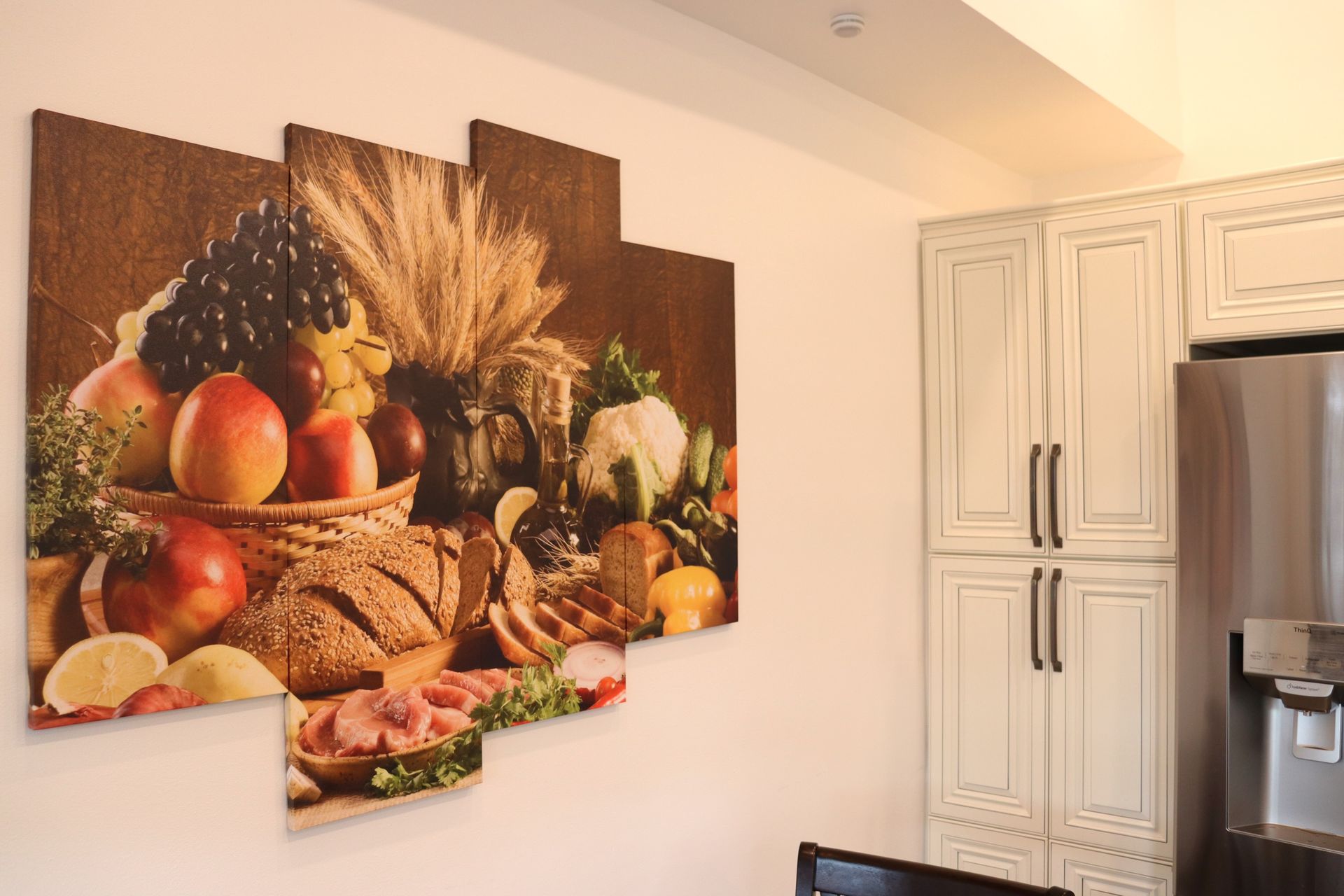 Une cuisine avec une peinture de fruits et légumes au mur.