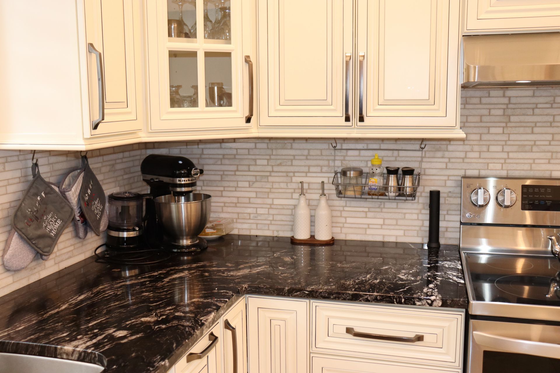 Une cuisine avec des armoires blanches, des comptoirs noirs, une cuisinière et un mixeur.