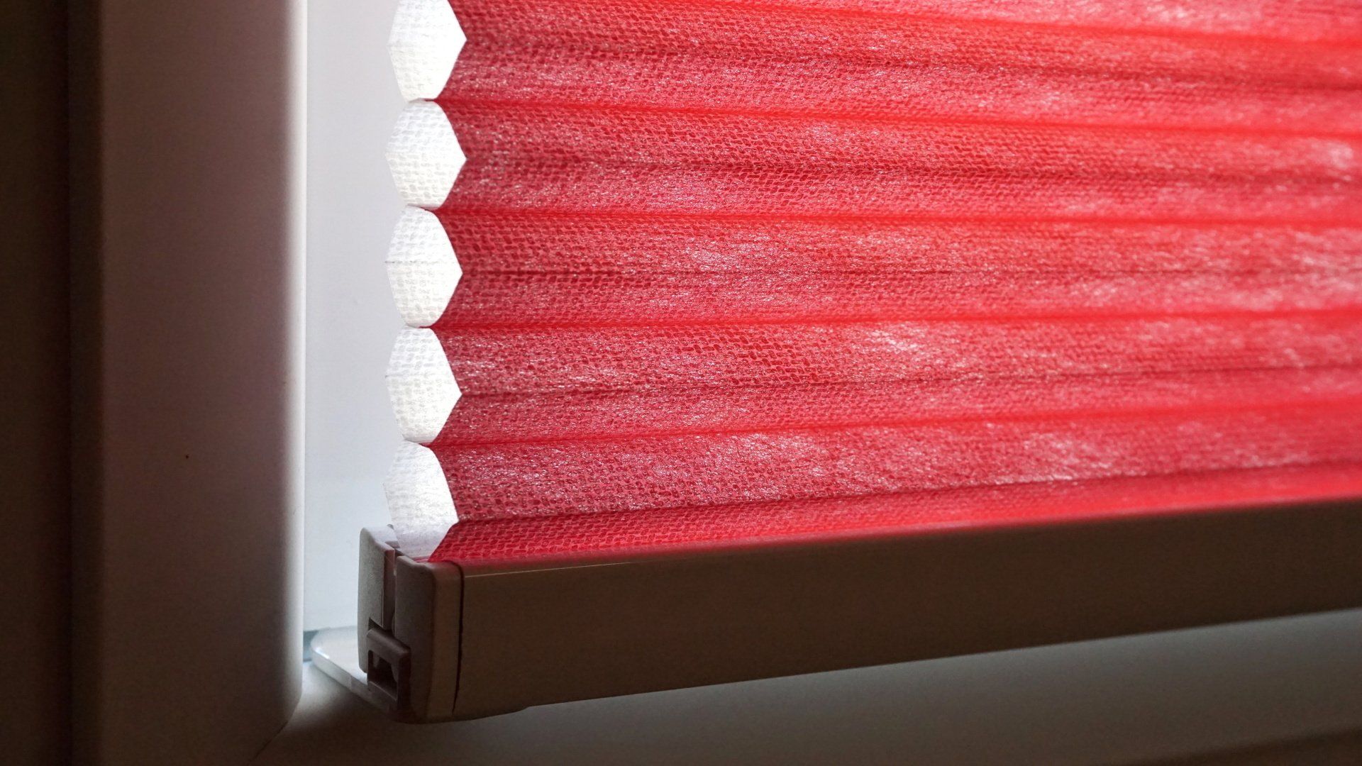 Un gros plan d'un store rouge sur une fenêtre.