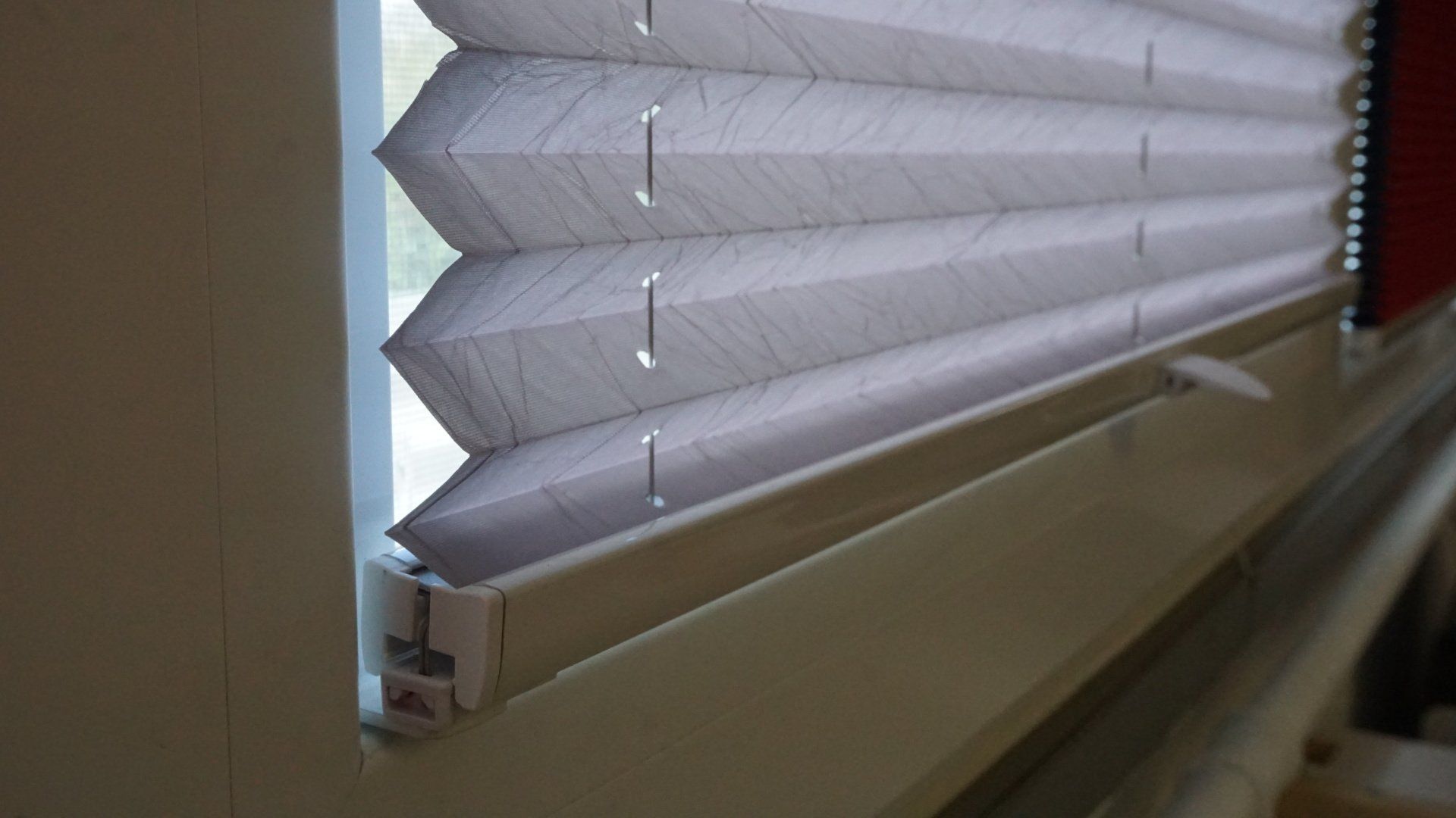 Un gros plan d'un store plissé sur une fenêtre.