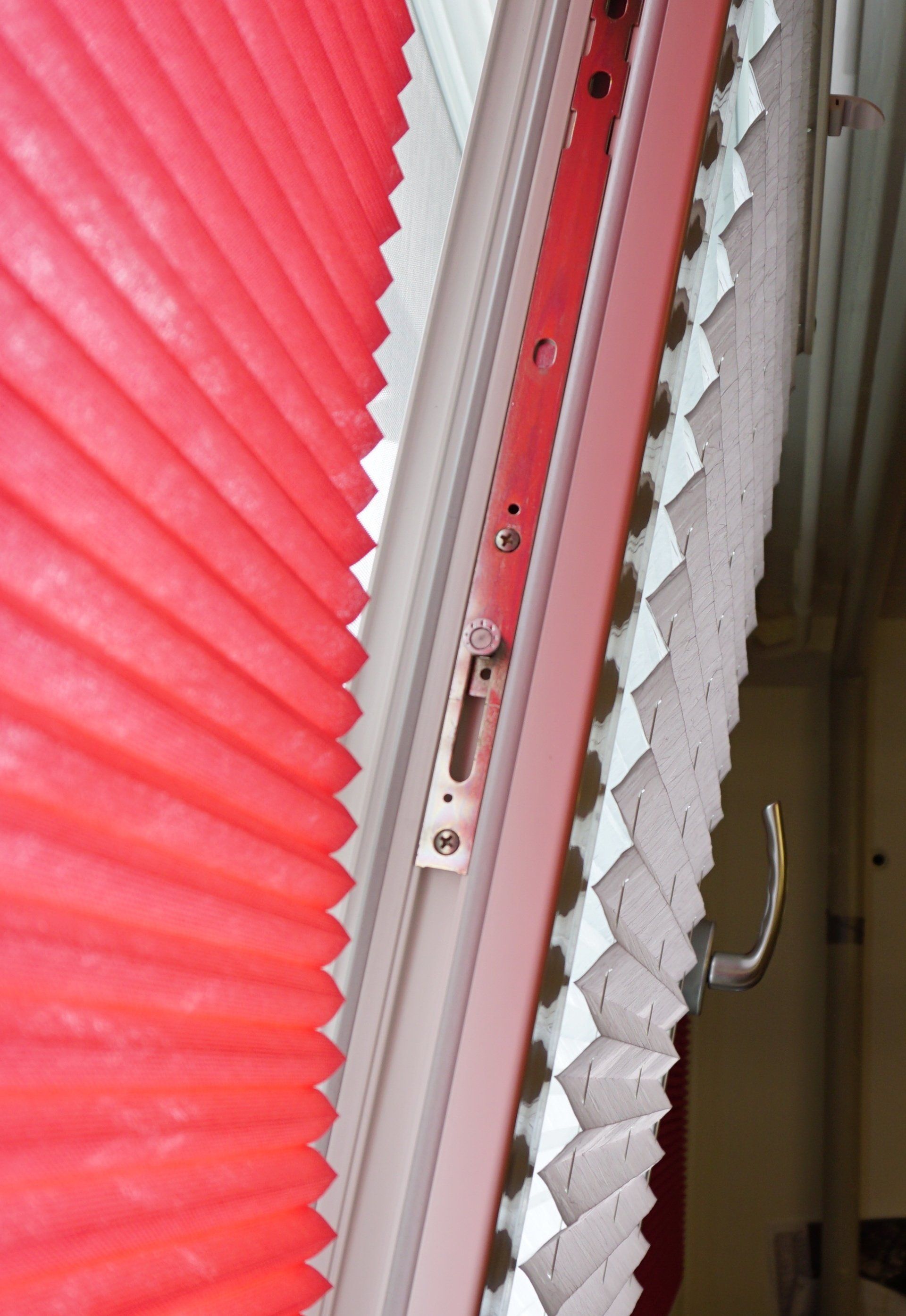 Un gros plan d'une fenêtre avec des stores plissés rouges