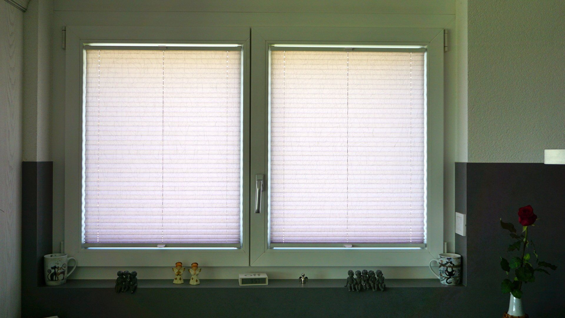 Une fenêtre avec des stores et un vase de fleurs sur le rebord de la fenêtre