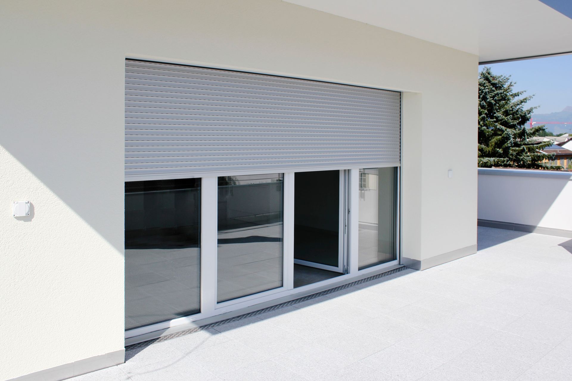 Un bâtiment blanc avec une porte coulissante en verre et un volet sur la fenêtre.