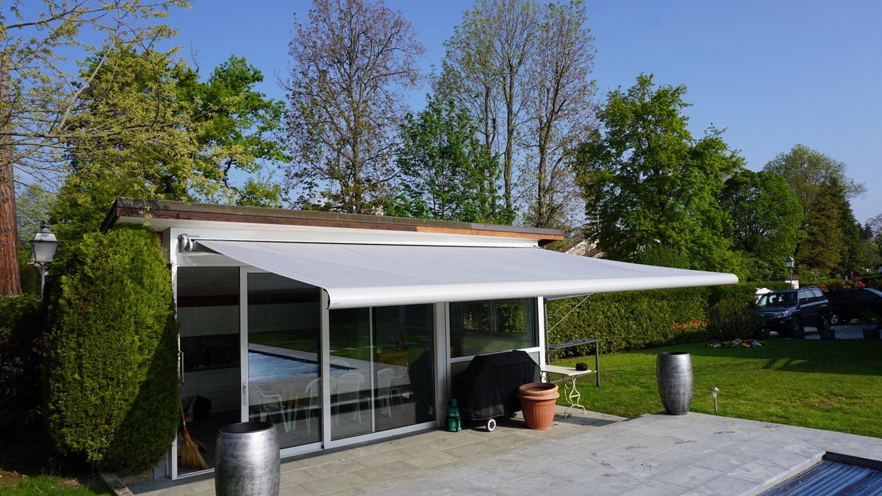 Un auvent blanc couvre un patio devant une maison.