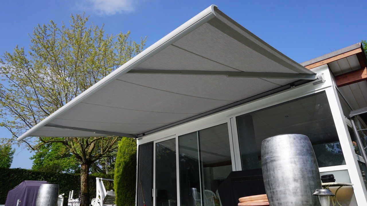 Un auvent blanc recouvre un patio avec des portes coulissantes en verre.