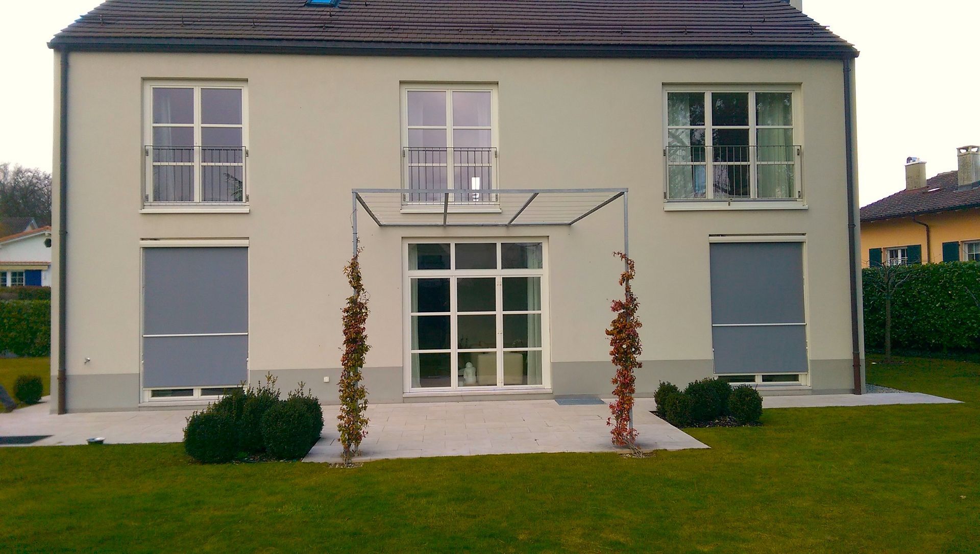 Une maison avec un balcon et des stores gris aux fenêtres