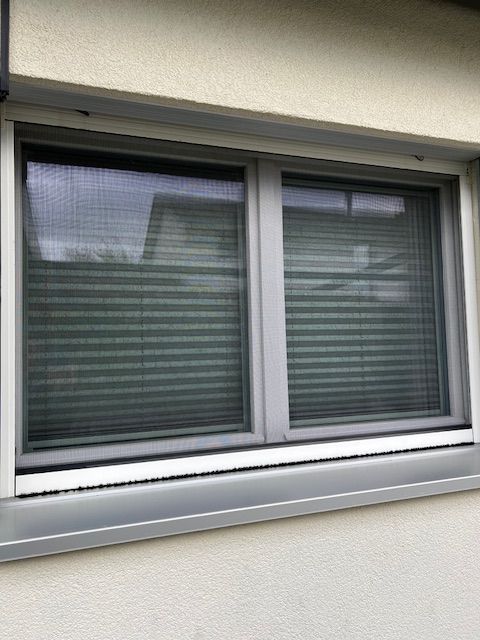 Une fenêtre avec des stores se trouve sur le côté d'un bâtiment.
