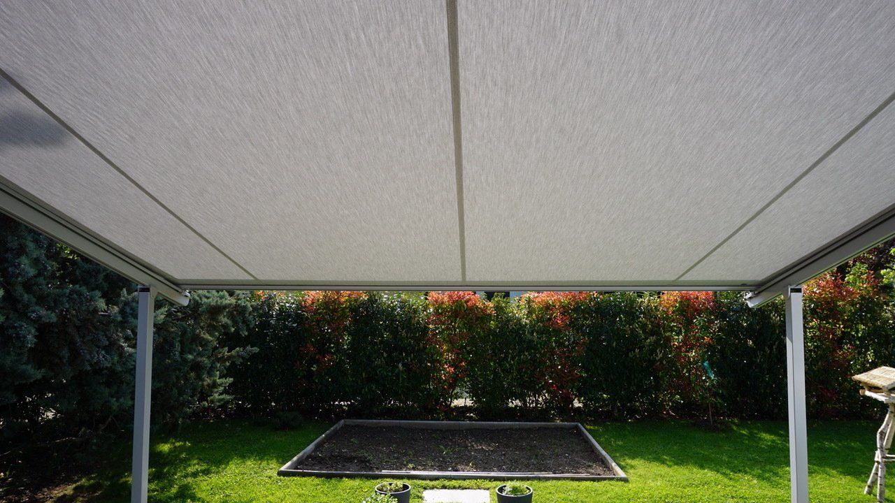 Un auvent blanc recouvre une pelouse dans une cour arrière.