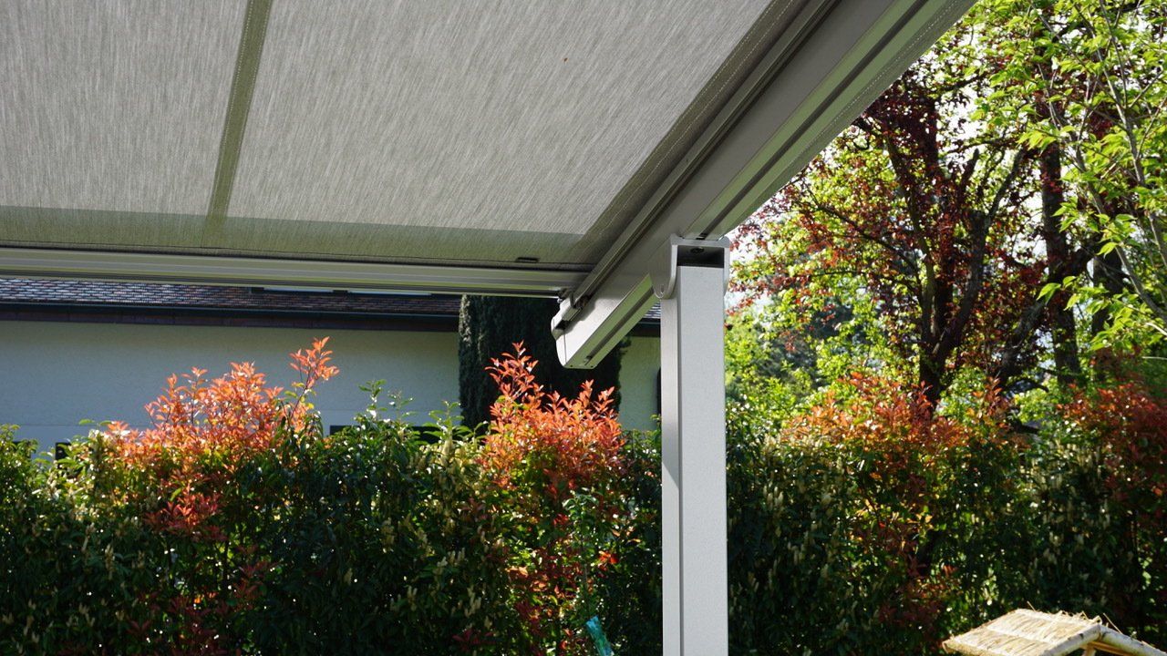 Un auvent blanc recouvre un patio dans une cour arrière.