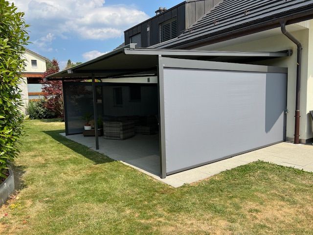 Une maison avec un patio couvert avec un écran sur le côté.