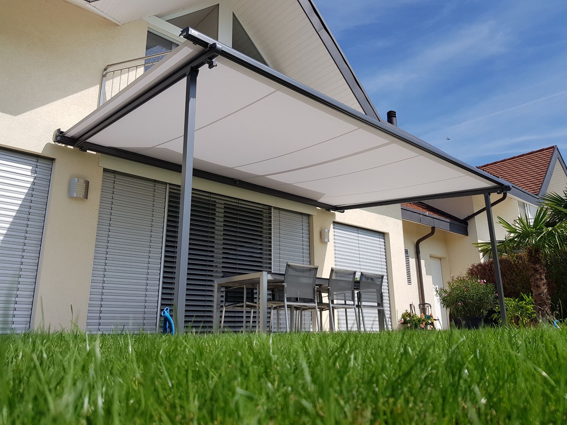 Une maison avec une table et des chaises sous un auvent