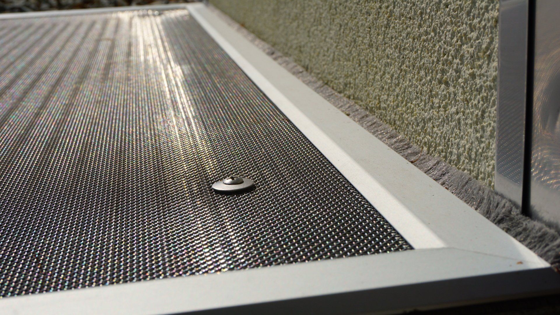 Un gros plan d'une porte moustiquaire avec une vis dedans.