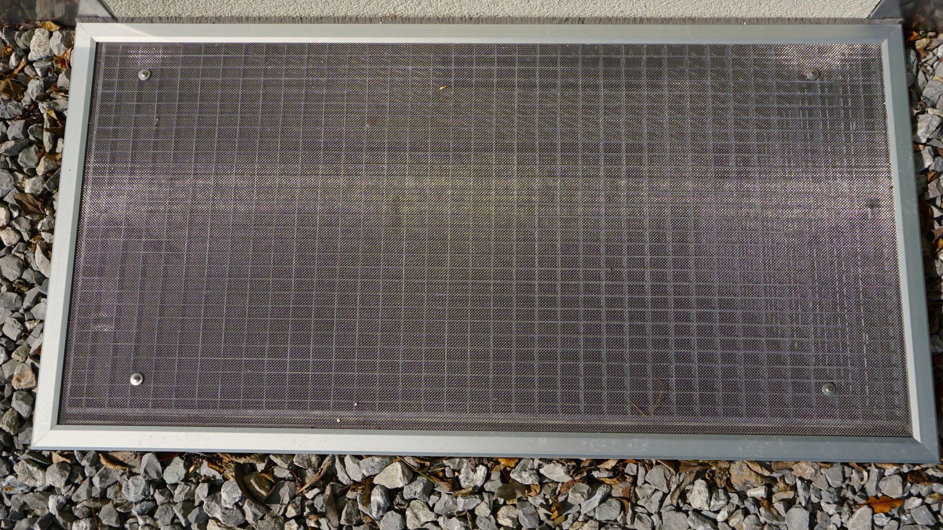 Un écran métallique est posé sur un tas de gravier.