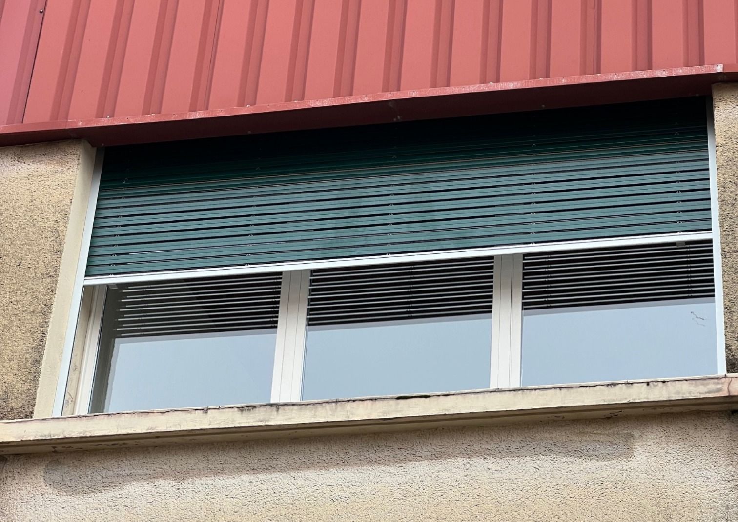 Une fenêtre avec un volet vert et un toit rouge