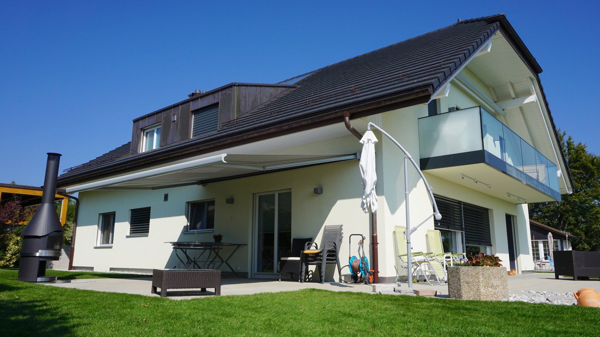Une grande maison blanche avec un balcon et une cheminée dans l'arrière-cour.