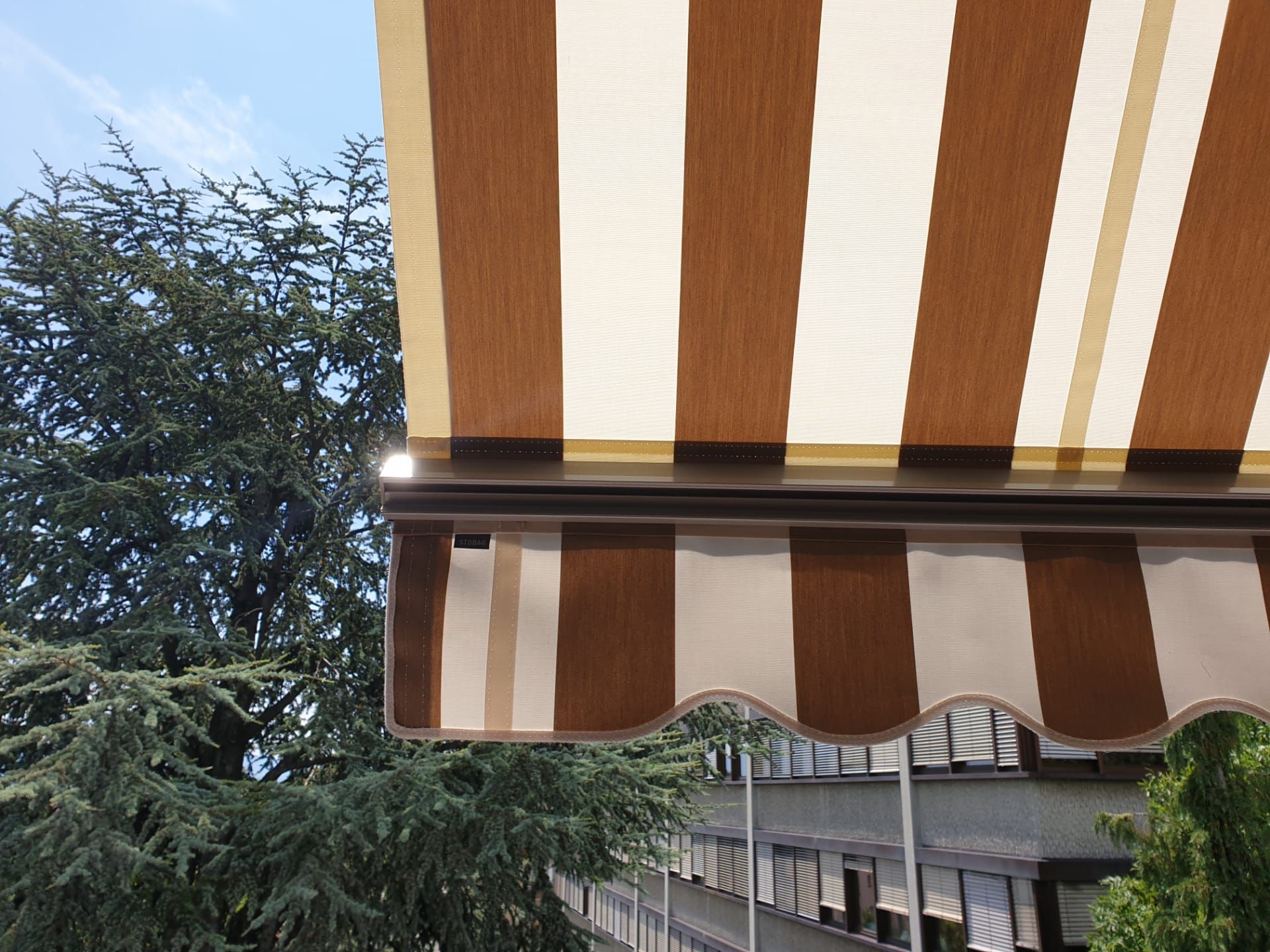 Un auvent rayé marron et blanc est suspendu au toit d'un bâtiment