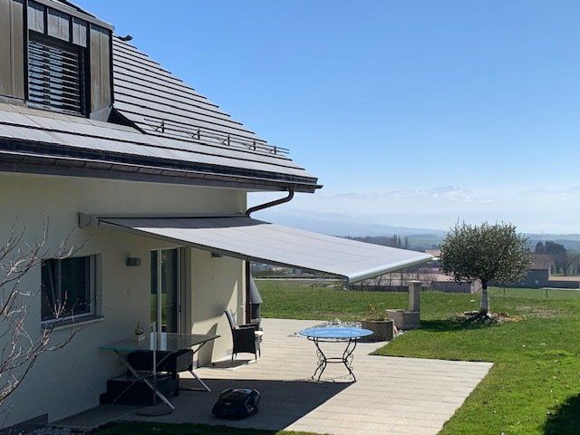 Une maison avec un patio avec une table et des chaises sous un auvent.
