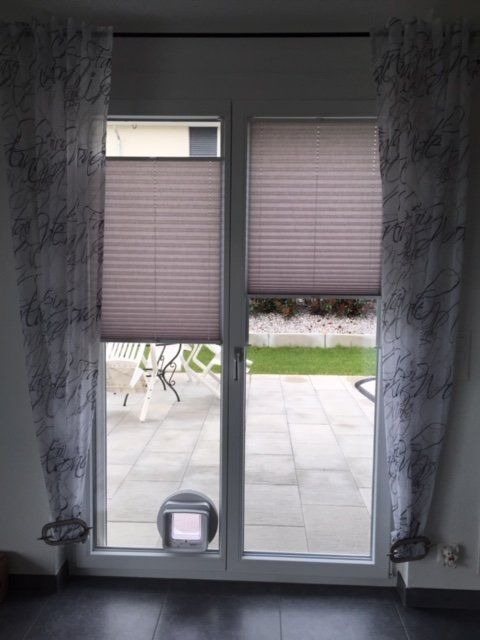 Une pièce avec une porte coulissante en verre et des stores dessus.