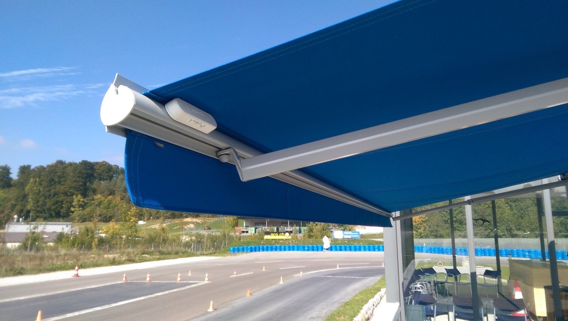 Un auvent bleu est posé au sommet d'un bâtiment à côté d'une autoroute.