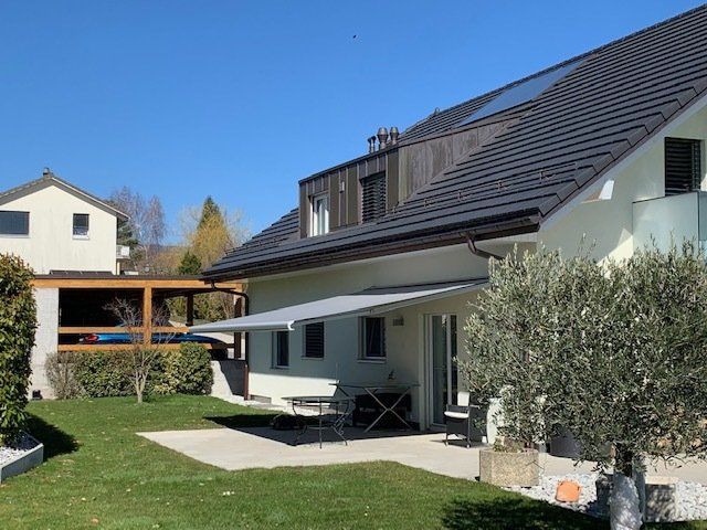 Une maison blanche avec un auvent gris dans l'arrière-cour