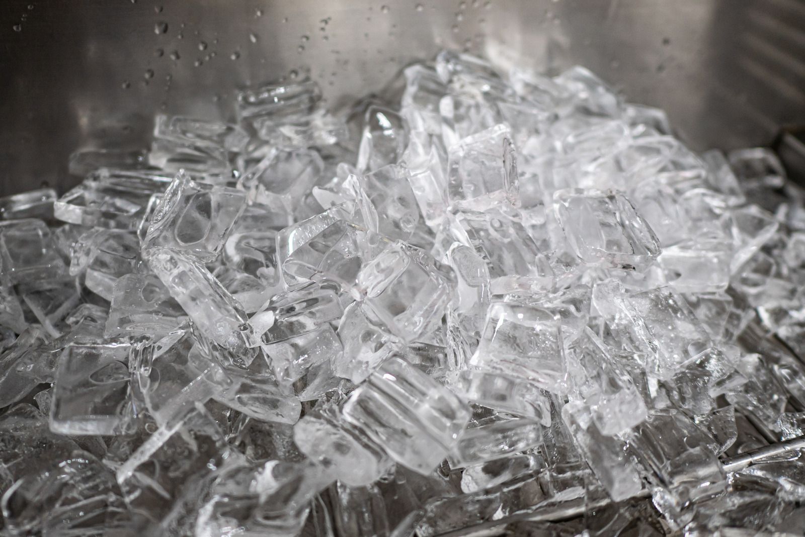 A pile of ice cubes in a metal bowl.