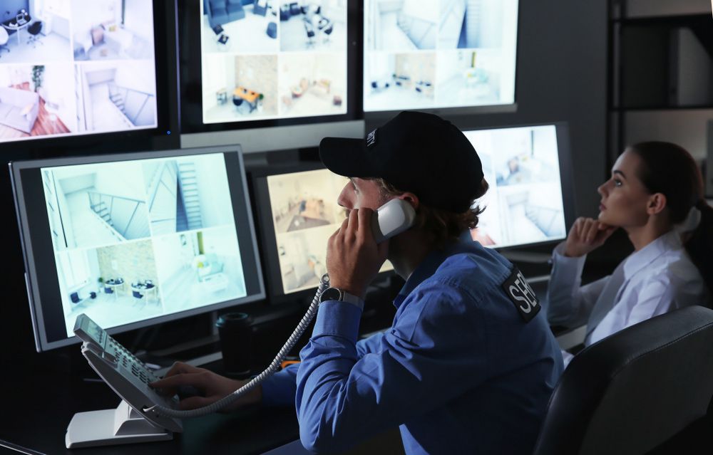 Security Guards Monitoring Modern CCTV and Holding Telephone - Security Company in Gilgandra, NSW