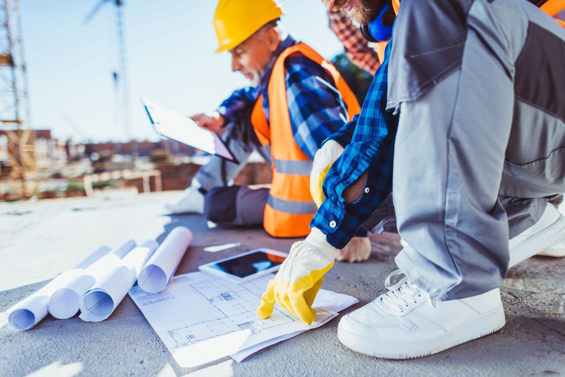 Un grupo de trabajadores de la construcción está mirando planos en un sitio de construcción.