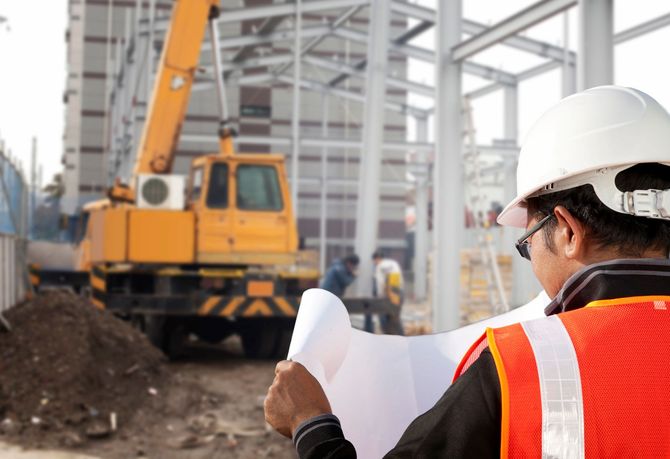 Un trabajador de la construcción está mirando un plano en un sitio de construcción.