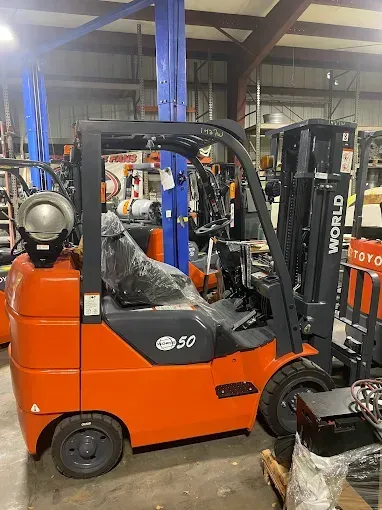 Orange Toyota forklift with black accents inside a warehouse.