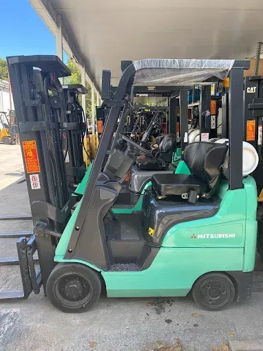 Green Mitsubishi forklift parked outdoors.